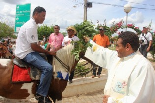 O vigário molhando o ramo dentro de um balde deu a benção a cada vaqueiro.