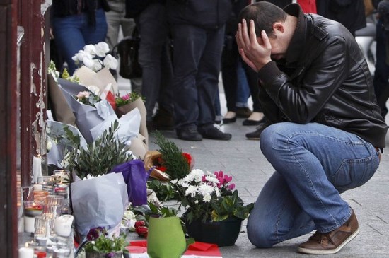 Homem se emociona diante de objetos de tributo deixados em frente à cafeteria Carillon, em Paris, onde um dos ataques terroristas ocorreu