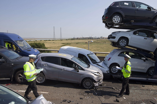 Policiais examinam os destroços dos carros esmagados na ponte Sheppey