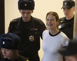 Ativista brasileira Ana Paula Alminhana Maciel sorri ao ser escoltada após conseguir liberdade provisória na Rússia